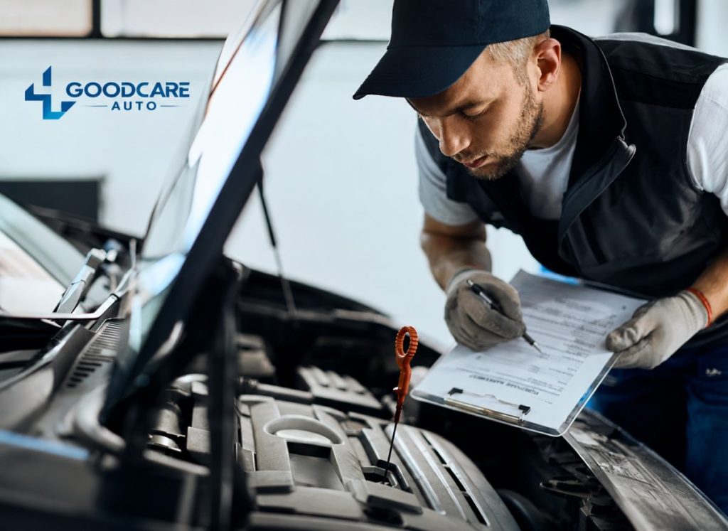 A mechanic is inspecting a car engine while holding a clipboard and the engine dipstick is visible.